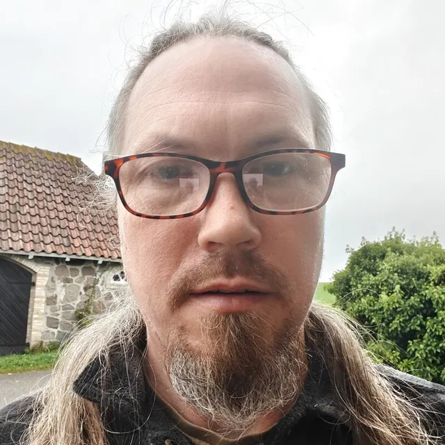 Foto af Paw udendørs med briller, langt hår og fipskæg